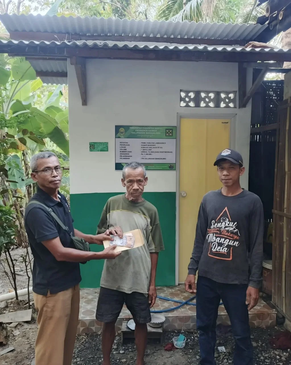 Penerima manfaat dan pendamping berdiri di depan bangunan jamban sehat di Padukuhan Salakan