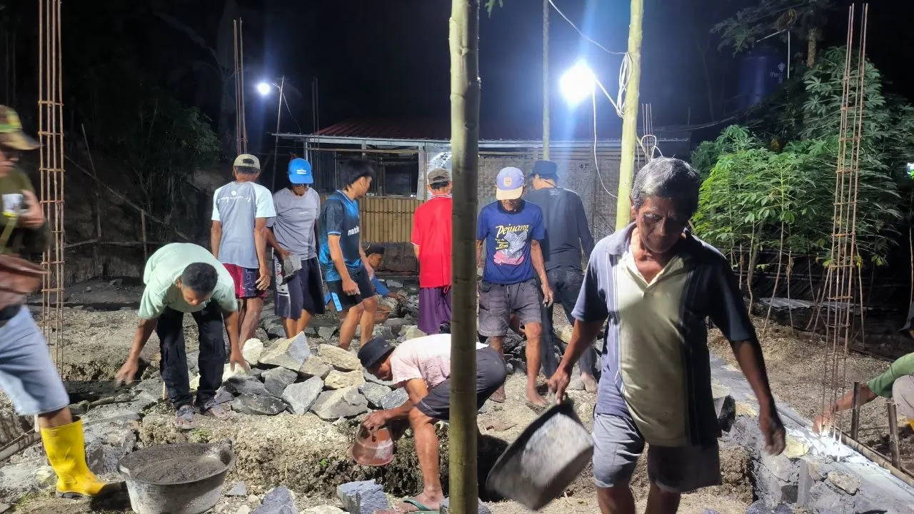Warga menyiapkan batu dan material pondasi dalam kegiatan gotong royong malam hari